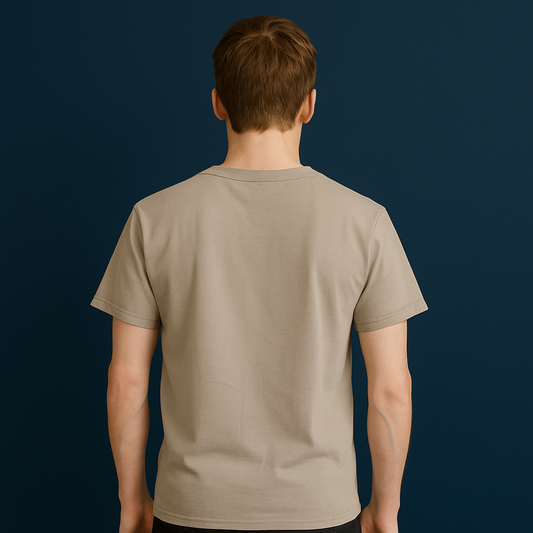 Back view of a beige plain drop shoulder t-shirt on a model against a blue wall.