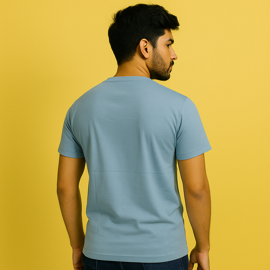 Back view of a man wearing a misty turquoise cotton spandex unisex t-shirt against a yellow background.
